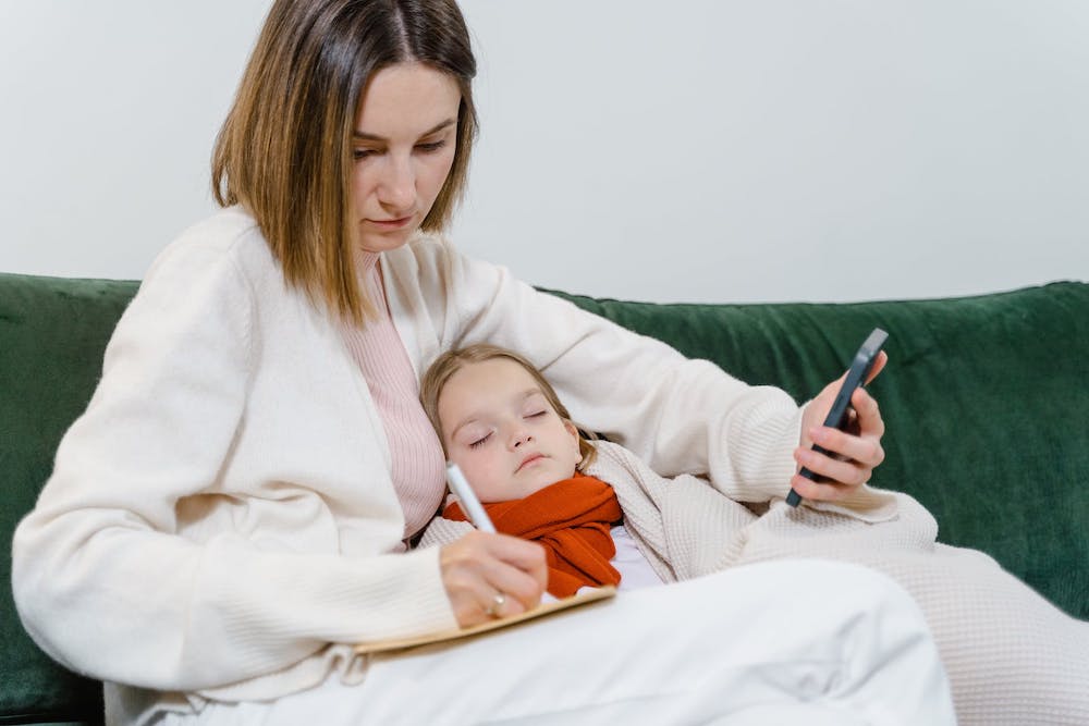 Working Mom mit krankem Kind im Arm - Arbeiten und Kinderbetreuung bei Krankheit