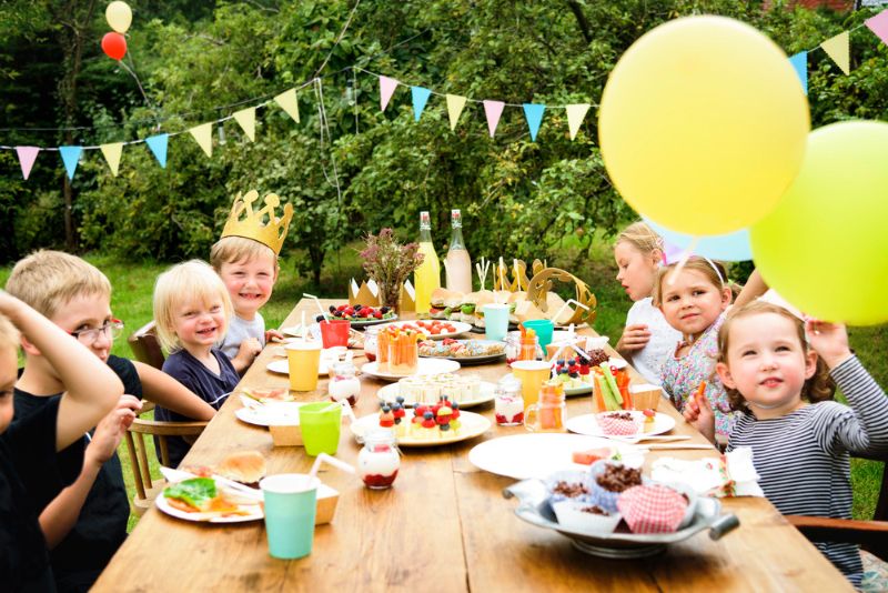 Kindergeburtstag - Essen und Trinken Kinder beim Essen am Geburtstagstisch