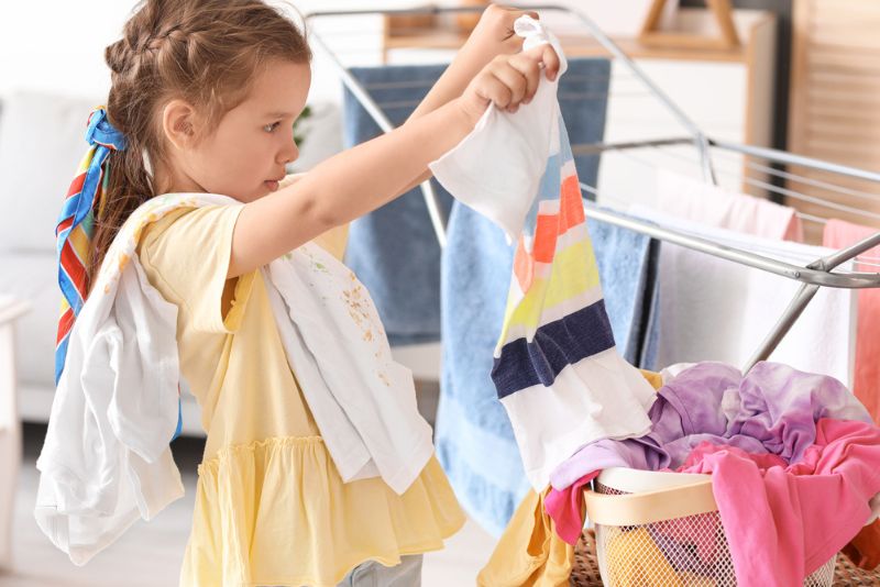 Wäsche machen - Kinder können helfen Mädchen hängt Wäsche auf den Wäscheständer