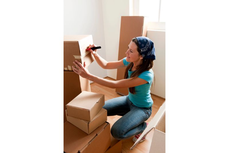 Frau beschriftet Umzugskartons